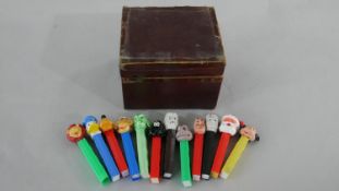 A collection of twelve vintage Pez sweet dispensers with various characters, accompanied by mahogany