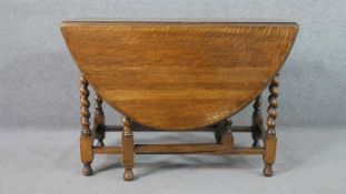 An early 20th century oak drop leaf dining table, with an oval top, on barley twist legs, joined