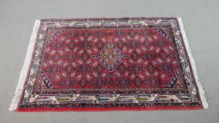 A red ground Persian handmade Hamadan rug. L.145 W.112cm