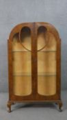 An Art Deco walnut display cabinet,with twin glazed doors and sides, enclosing glass shelves, on