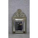 A Louis XV style repousse brass cushion framed wall mirror with bevelled plate and stylised
