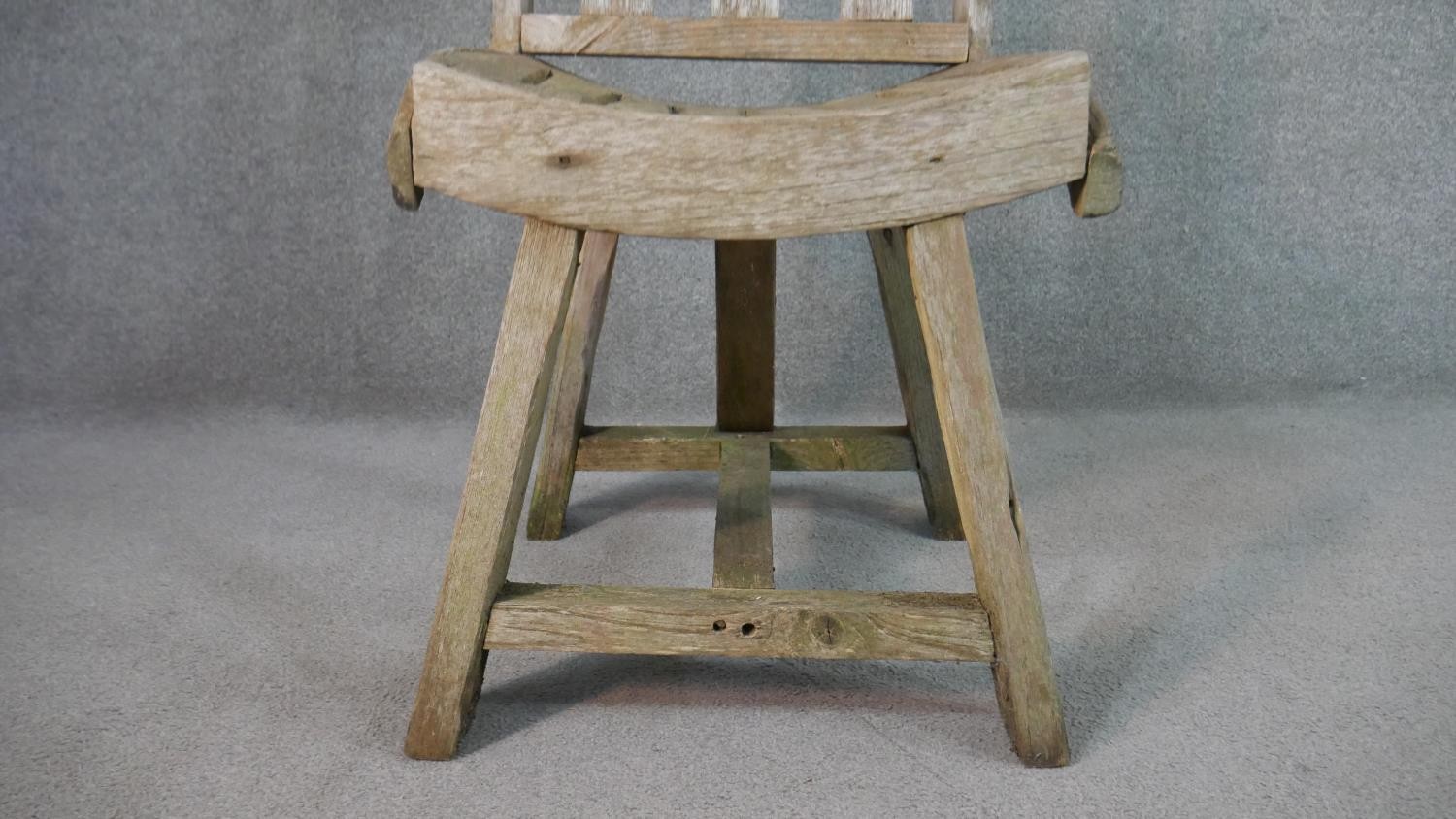 A rustic wooden garden chair, the three splat back over a curved slatted seat, the legs joined by an - Image 5 of 5