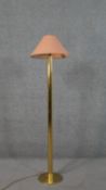 A brass standard lamp, with a salmon coloured shade, on a cylindrical stem with a circular base. H.