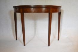 A Georgian mahogany demi lune tea table with fold over top on square tapering gateleg supports. (