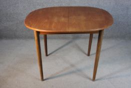 A circa 1970s G-Plan teak dining table, of eliptical form with a butterfly leaf, on tapering
