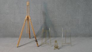 A collection of easels, including a pine artists easel, a baroque style brass easel and two other