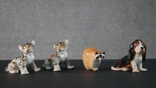 A collection of Lomonosov porcelain animals, including two tiger cubs, a racoon and a Basset Hound