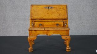A George I style elm apprentice piece bureau, with a fall front enclosing a fitted interior, over