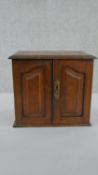 A late Victorian oak tabletop smoker's cabinet, with a rising lid and two panelled doors,