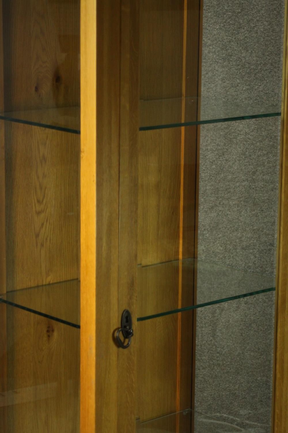 A contemporary honey oak display cabinet, with glazed door and sides, enclosing glass shelves. H.180 - Image 7 of 9