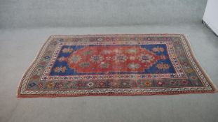 A red ground handmade Caucasian rug. L.230 W.130cm