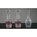 A pair of early 20th century Bohemian cut crystal decanters with painted ruby central bands engraved