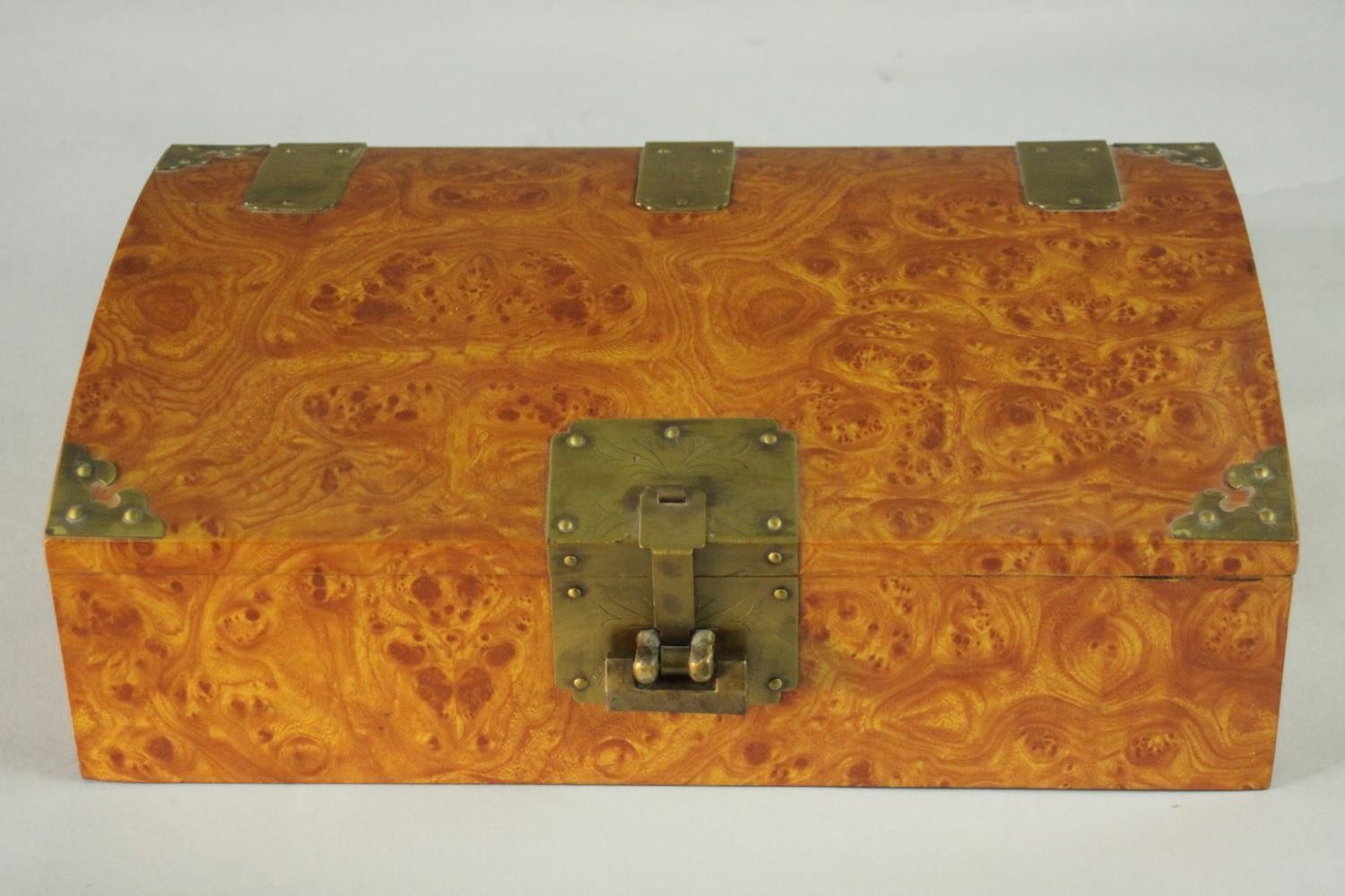 A burr walnut veneer Chinese style jewellery box with brass fittings with padlock (no key), paper