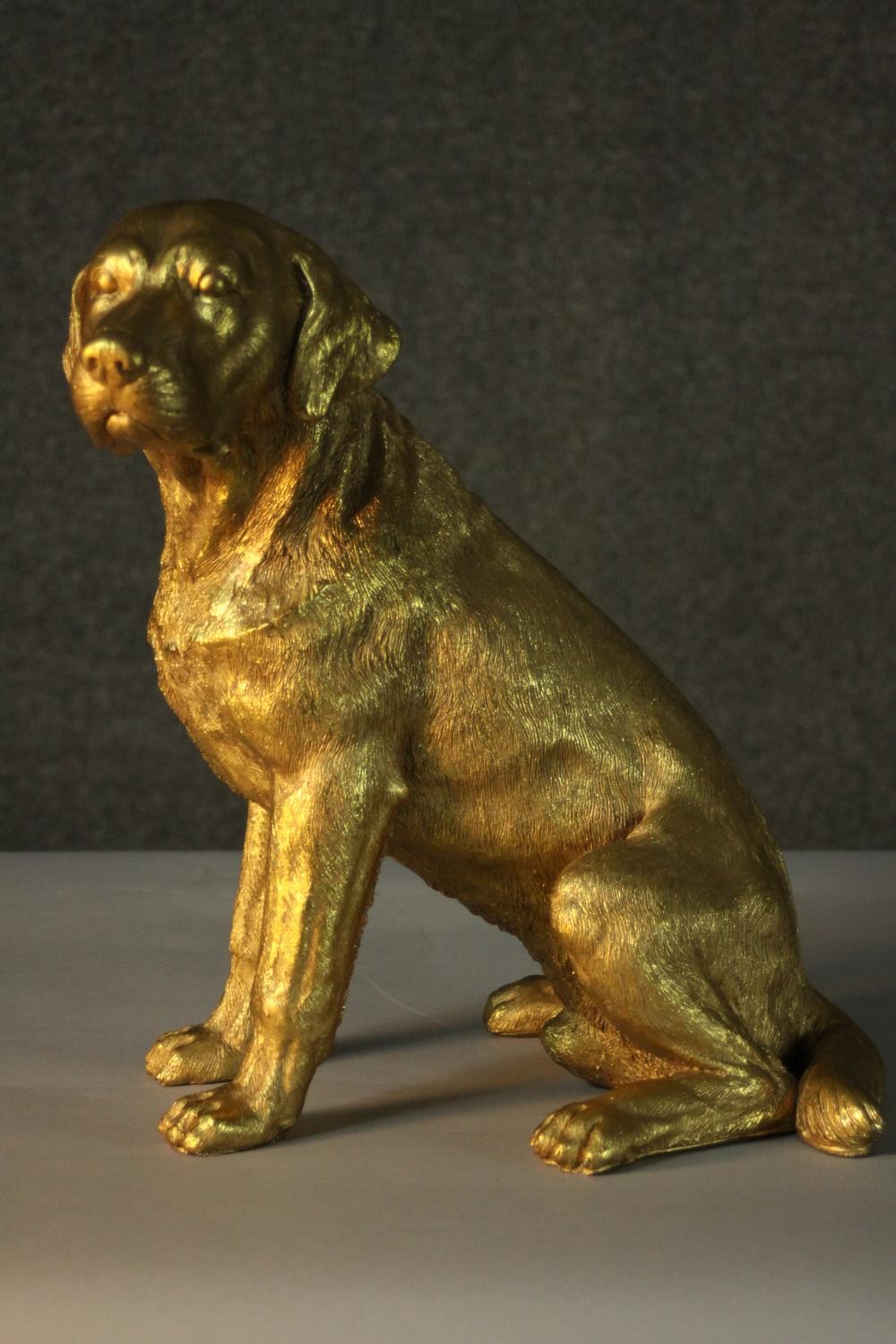 A gilded resin sculpture of a seated Labrador. H.15cm.