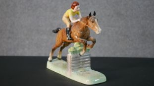 A Beswick hand painted ceramic model of a lady jockey in yellow shirt jumping a fence, makers mark