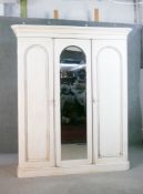 A white painted Victorian triple wardrobe, with a mirror to the central door, enclosing hanging