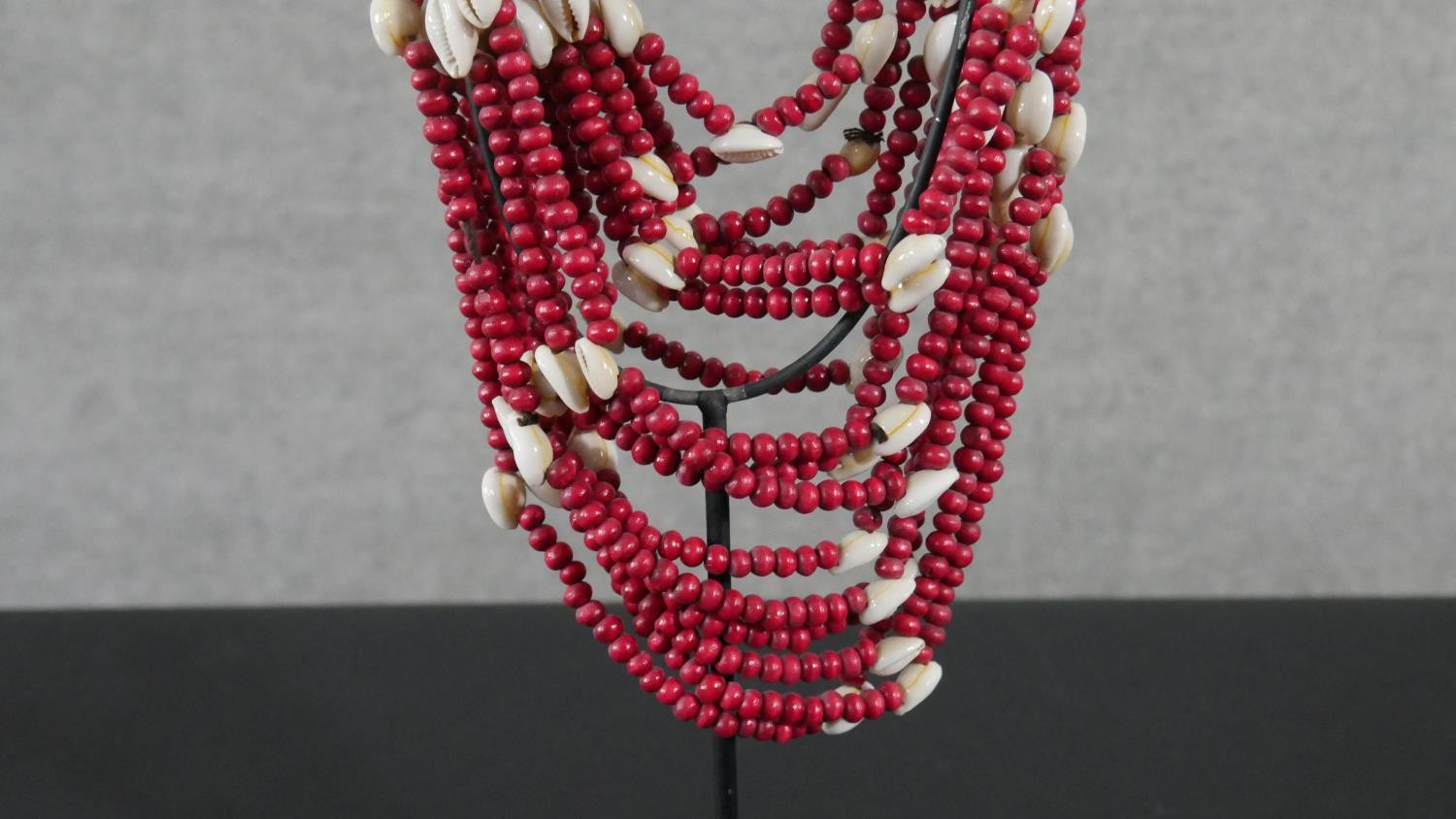 A tribal wooden bead and cowrie shell multi stranded necklace on metal display stand. H.56 W.12 D. - Image 5 of 5