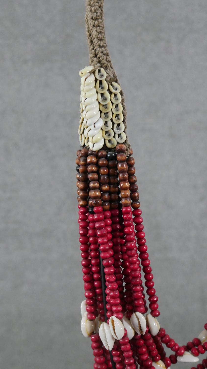 A tribal wooden bead and cowrie shell multi stranded necklace on metal display stand. H.56 W.12 D. - Image 4 of 5