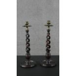 A pair of Art Nouveau oak and brass spiral design candle sticks with embossed design to the brass
