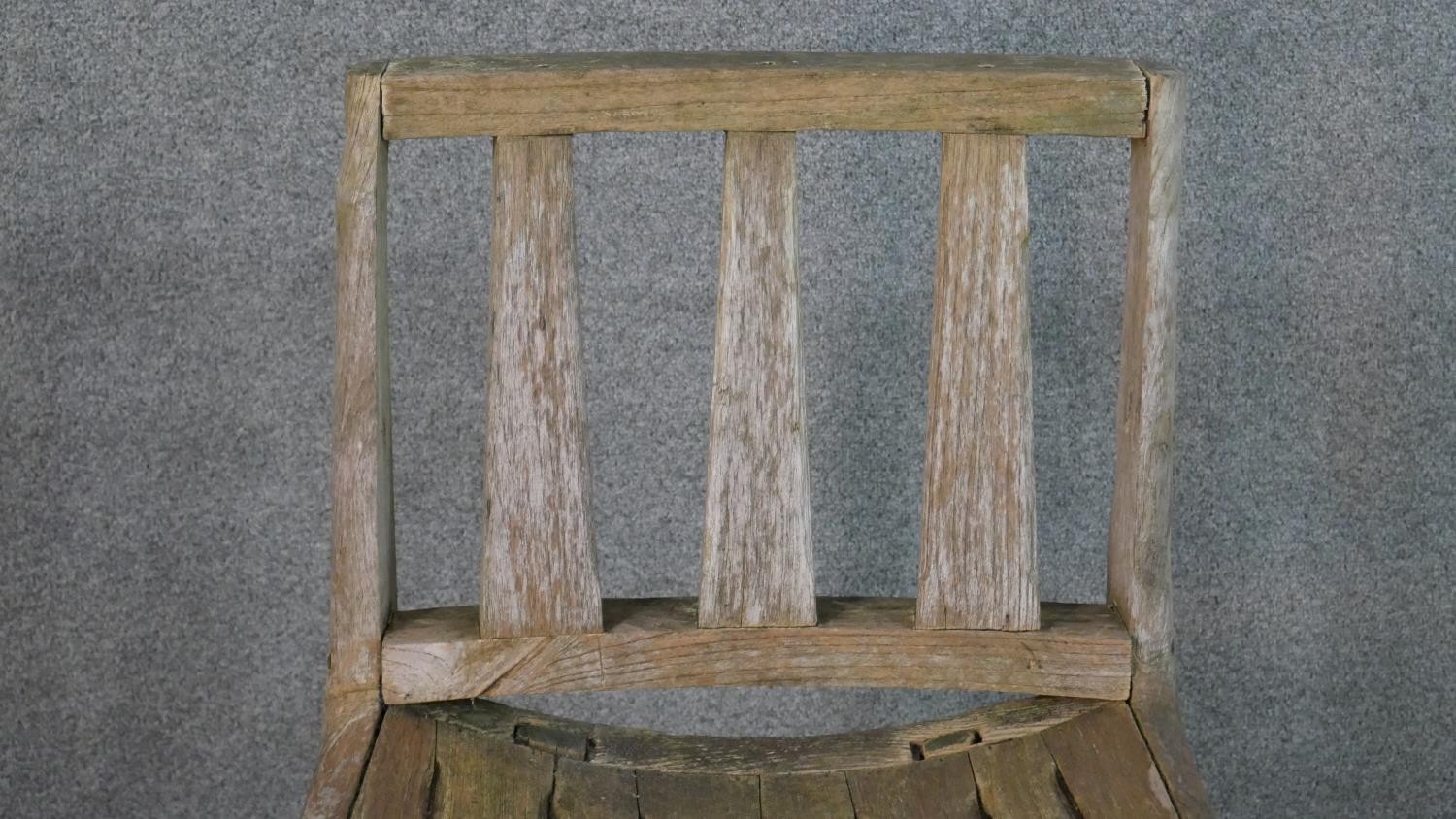 A rustic wooden garden chair, the three splat back over a curved slatted seat, the legs joined by an - Image 4 of 5