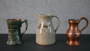 Two art pottery jugs and a 19th century copper pint measure by T. Callam. H.18 W.15cm (largest)