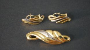 A boxed 18 carat white and yellow gold swirl scrolling design brooch and matching pierced