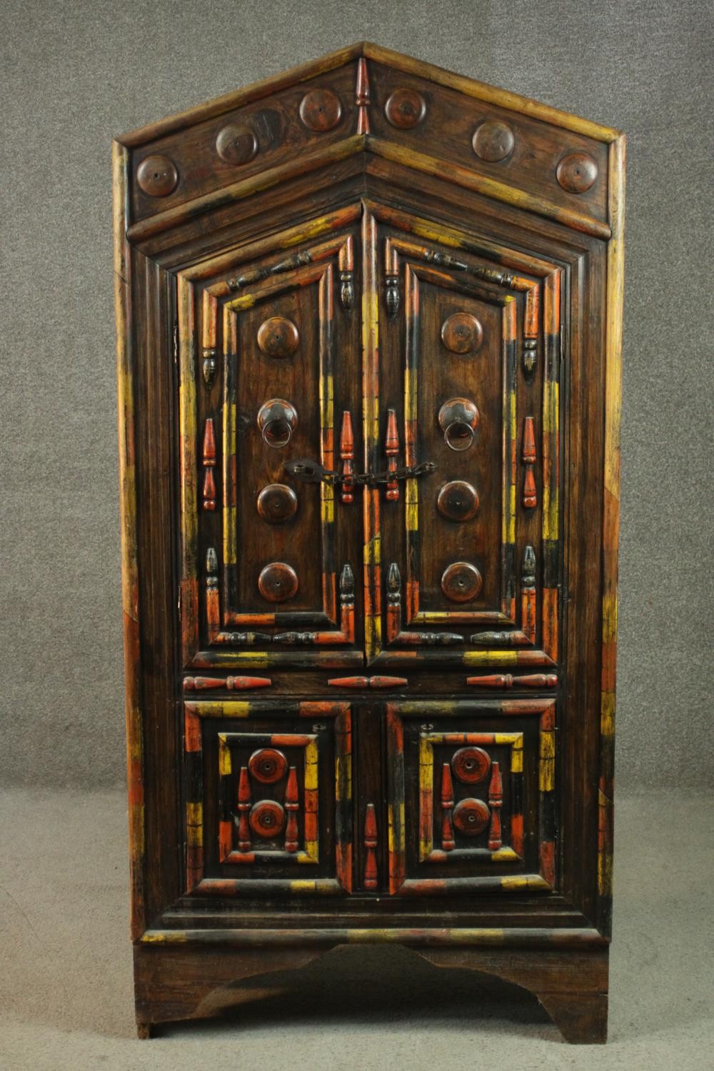 An Indian polychrome painted hardwood cupboard, with an arch top over two pairs of cupboard doors,