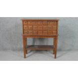 A teak spice cabinet on stand, with three rows of seven short drawers, on square section tapering