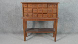 A teak spice cabinet on stand, with three rows of seven short drawers, on square section tapering