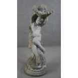 A large reconstituted stone bird bath in the form of a nude female holding a sea shell. Indistinctly