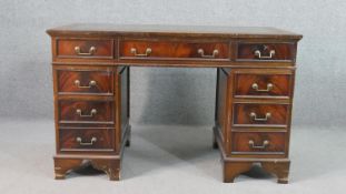 A mahogany pedestal desk, with a tooled green leather writing surface over an arrangement of nine
