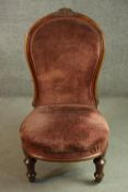 A Victorian walnut nursing chair, upholstered in velour, on turned and fluted legs.