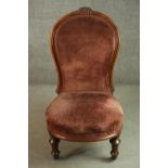 A Victorian walnut nursing chair, upholstered in velour, on turned and fluted legs.