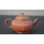 A 19th century Yixing clay gadrooned form miniature tea pot with floral design lid, impressed four