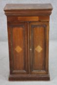 An Edwardian walnut tabletop cabinet, the two doors enclosing a white painted interior with shelves,