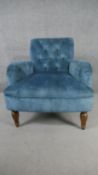 A contemporary Victorian style armchair, upholstered in blue velour, with a button back, on turned