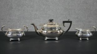 A three-piece tea service with gadrooned and shell borders comprising: a teapot with ebonised