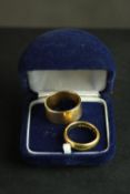 Two yellow gold wedding bands. A wide 18 carat gold D-shape court band and a 22 carat gold wide flat