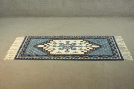 A Tibetan cream ground handmade rug. H.168 W.77cm.