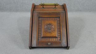 A Victorian Aesthetic Movement walnut coal scuttle, with a brass flowerhead, the rising lid carved