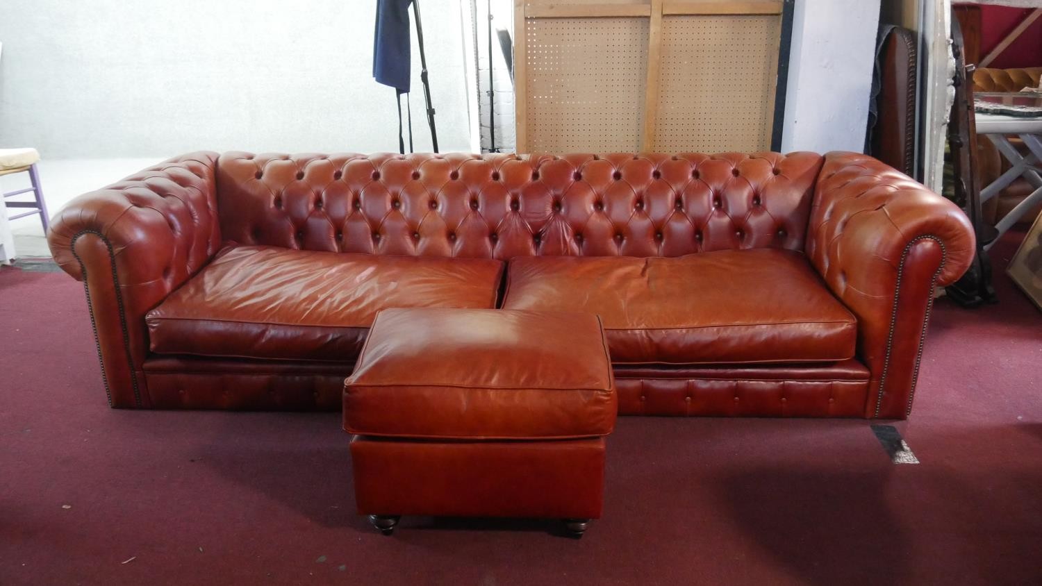 A large red leather Chesterfield sofa, with a button back and scroll arms, together with a leather