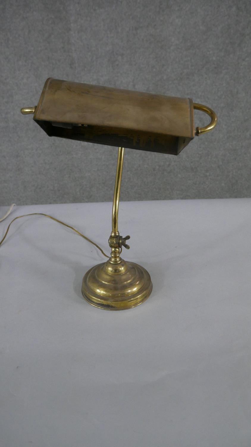 A brass bankers desk lamp, with a curved adjustable stem, on a circular footed base. H.45 W.28cm