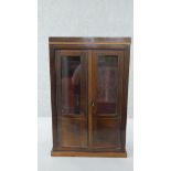 An Art Deco rosewood apprentice piece display cabinet, with a pair of glazed doors, on a plinth