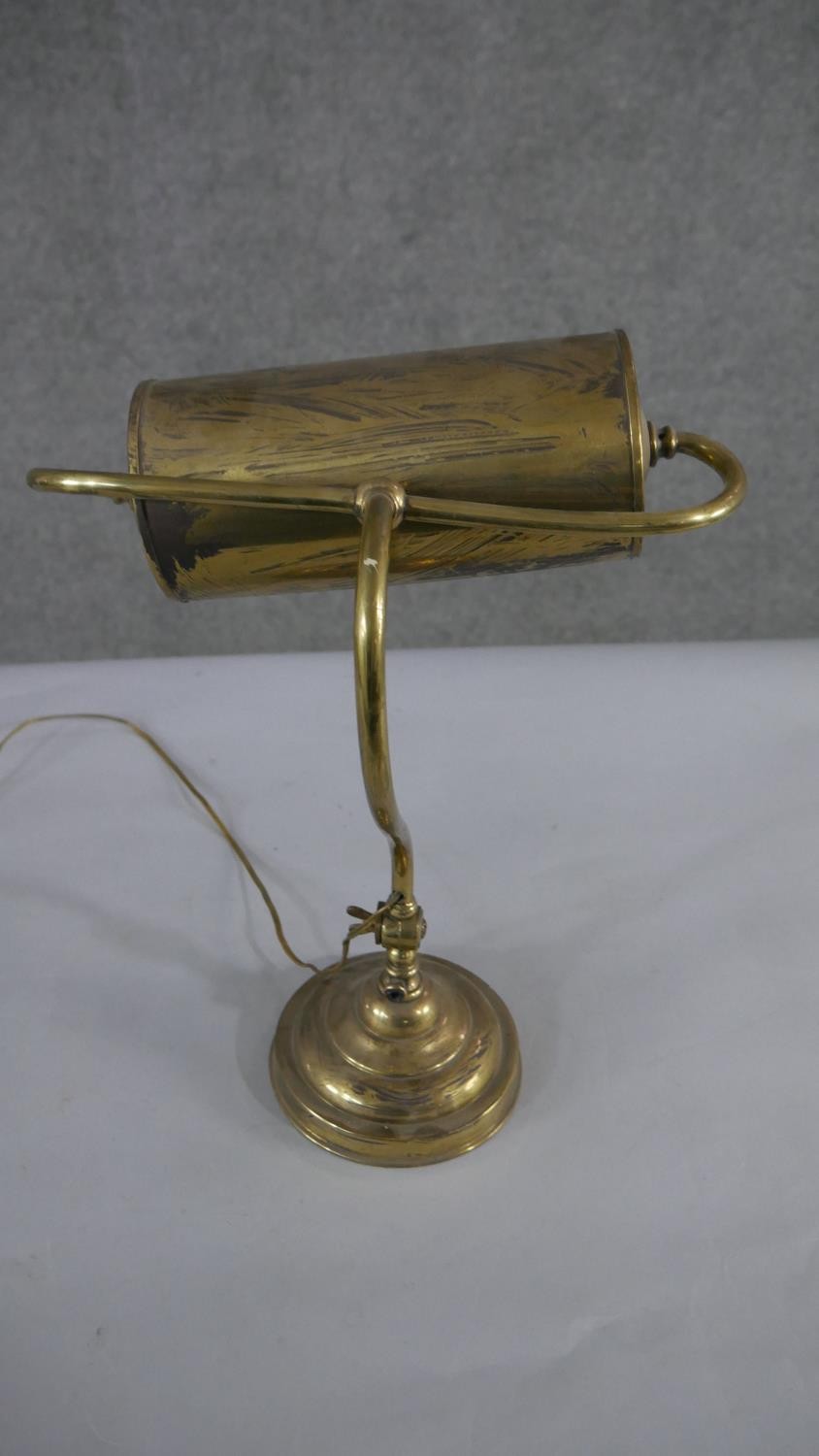 A brass bankers desk lamp, with a curved adjustable stem, on a circular footed base. H.45 W.28cm - Image 4 of 4