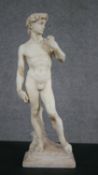 A carved alabaster model of David, after Michelangelo, standing holding a dead serpent over his