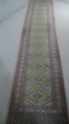 A green ground Bokhara motif runner. L.350 W.70cm