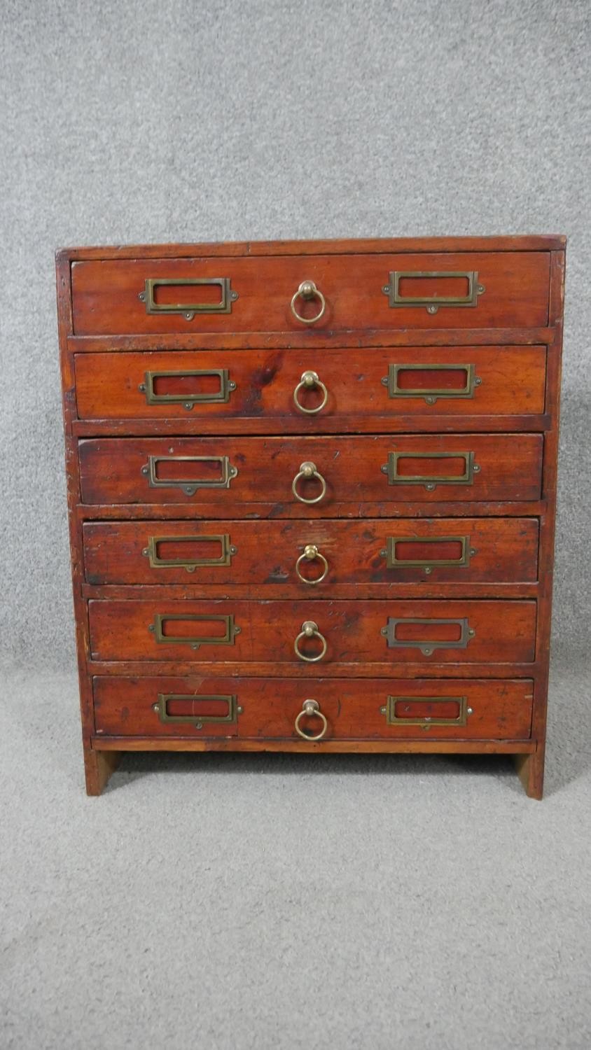 A stained pine collectors cabinet, the six long drawers with brass ring handles and fitted