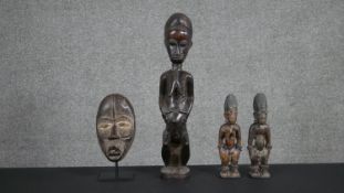 An African carved tribal mask on stand, a pair of carved African figures and a larger African carved