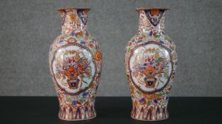 A pair of early 20th century Chinese hand painted vases with panels decorated with flower baskets