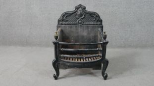 A cast iron fire basket, the back cast with a shell, with brass urn finials, on cabriole legs. H.